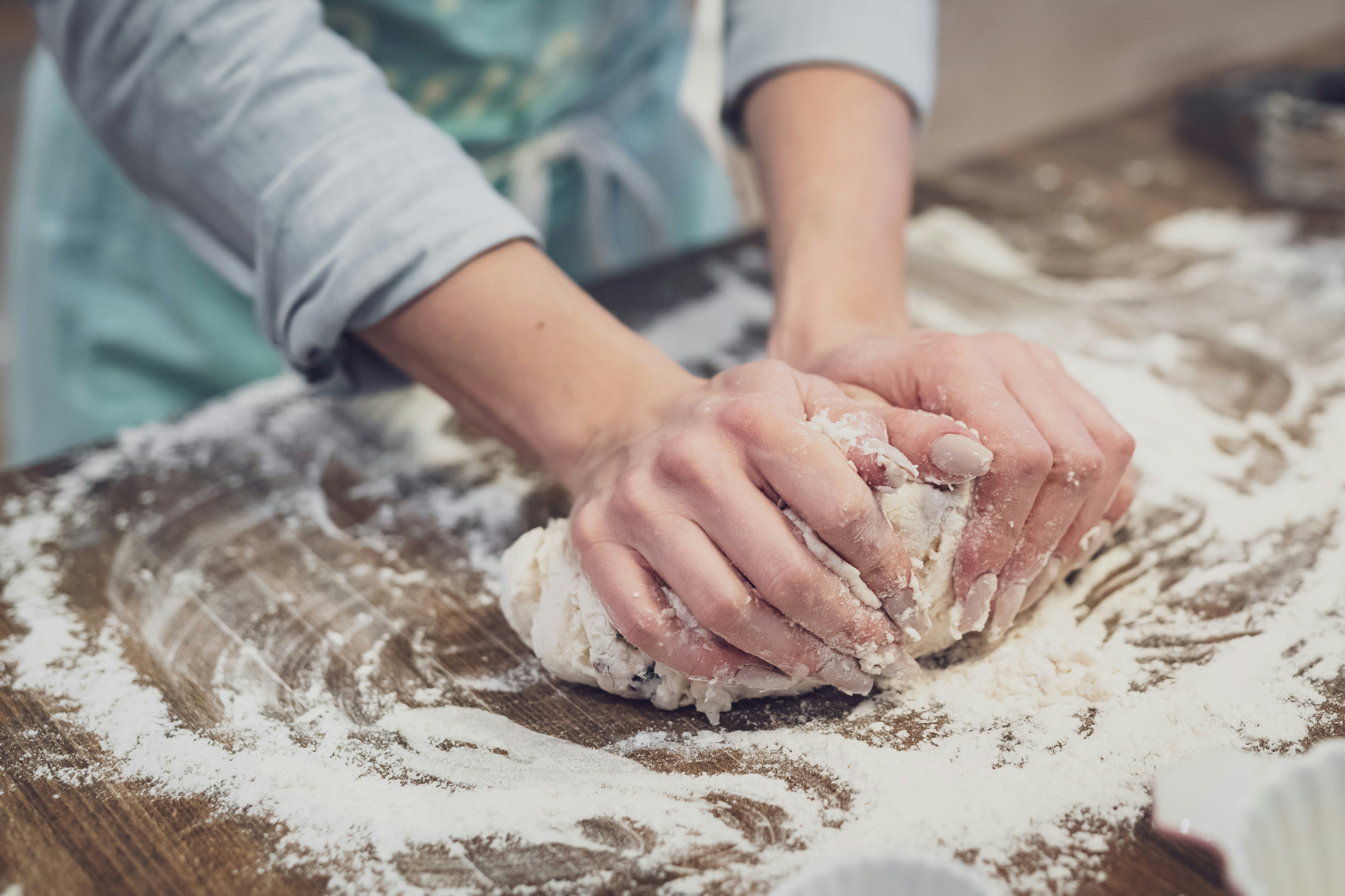 person kneading dough by hand on a wooden countertop