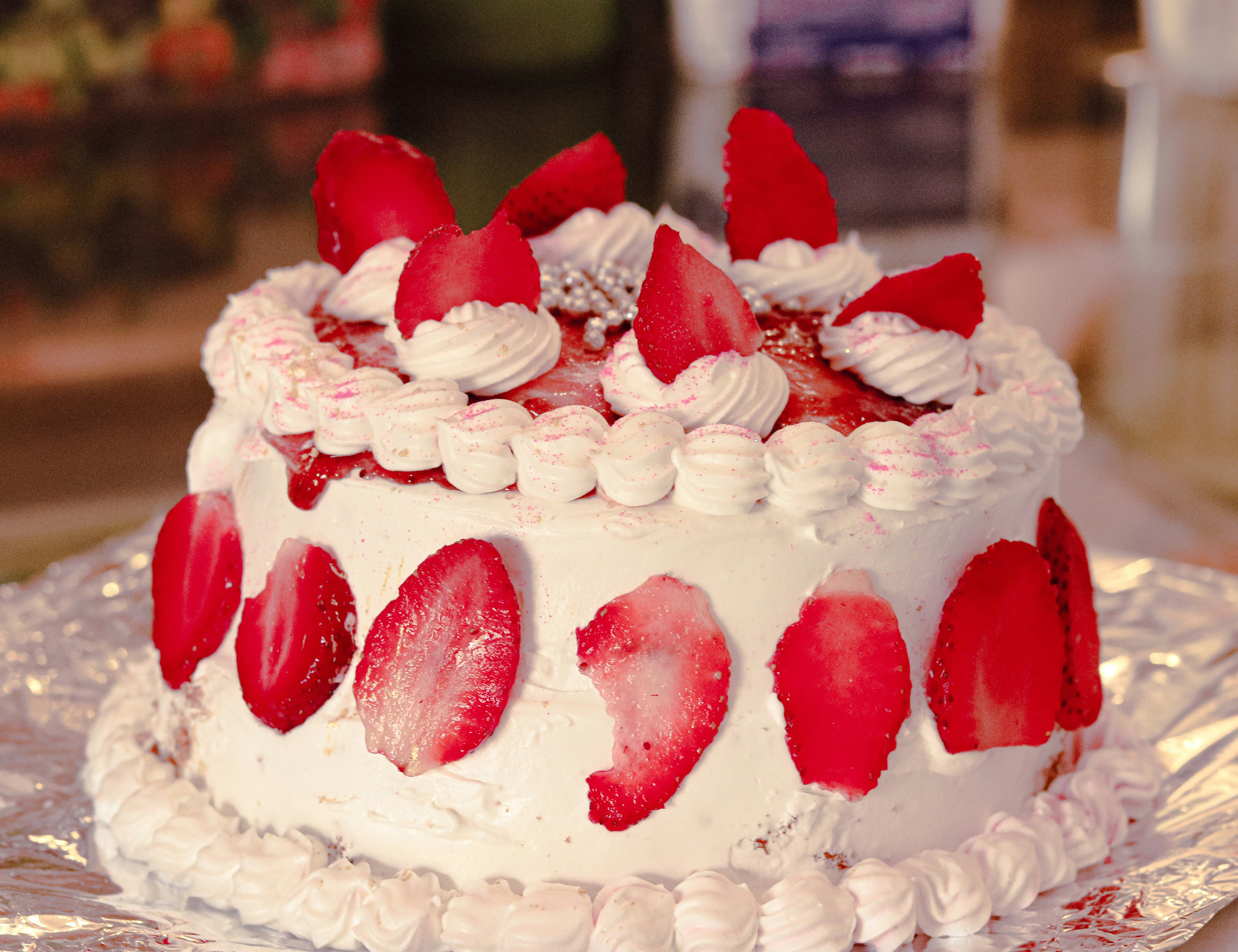 homemade strawberry shortcake decorated with white frosting and strawberries on tin foil